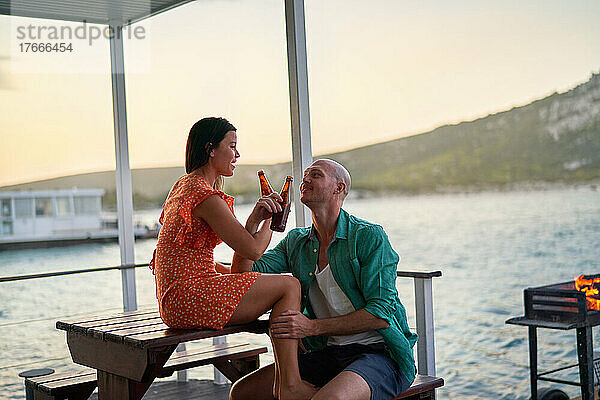 Glückliches Paar trinkt Bier auf der Terrasse des Hausboots