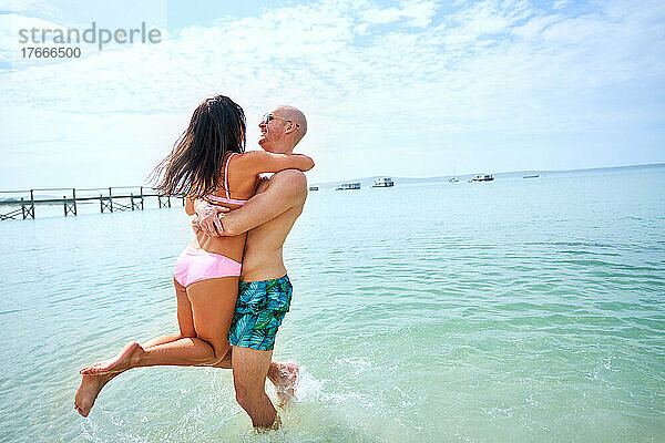 Glückliches  unbeschwertes Paar  das im sonnigen Sommermeer spielt