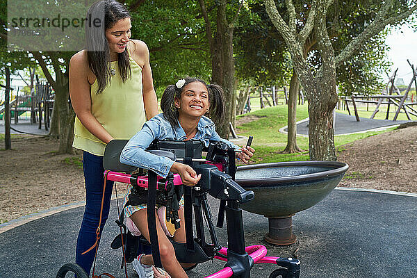 Mutter und glückliche behinderte Tochter im Rollator im Park