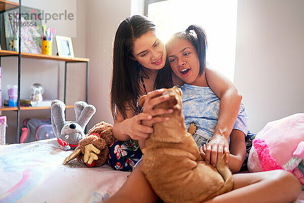 Mutter und behinderte Tochter mit süßem Hund zu Hause im Bett