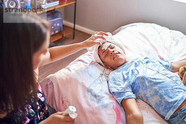 Mutter gibt ihrer behinderten Tochter zu Hause im Bett eine Gesichtsbehandlung