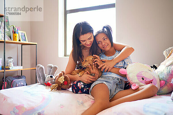 Glückliche Mutter und behinderte Tochter mit süßem Hund im Bett