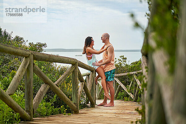 Glückliches Paar  das sich auf der Strandpromenade von Angesicht zu Angesicht unterhält