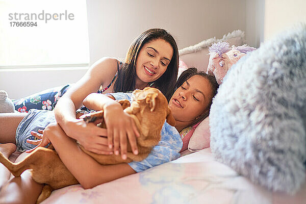 Mutter und Tochter liegen zu Hause mit Hund im Bett