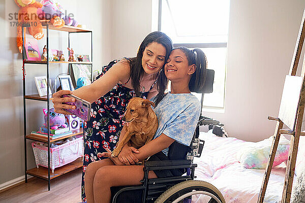 Glückliche Mutter und behinderte Tochter mit Hund machen zu Hause ein Selfie