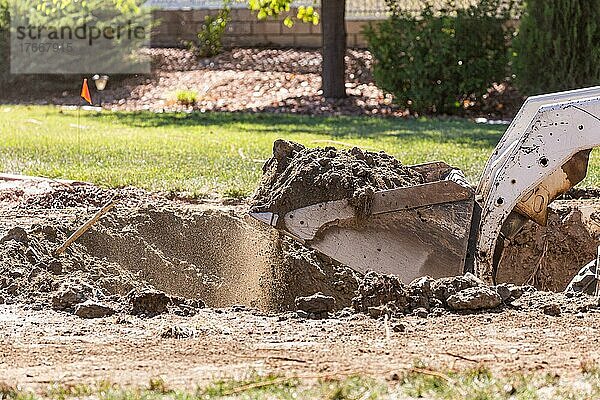 Kleiner Bulldozer gräbt im Hof für die Installation eines Pools