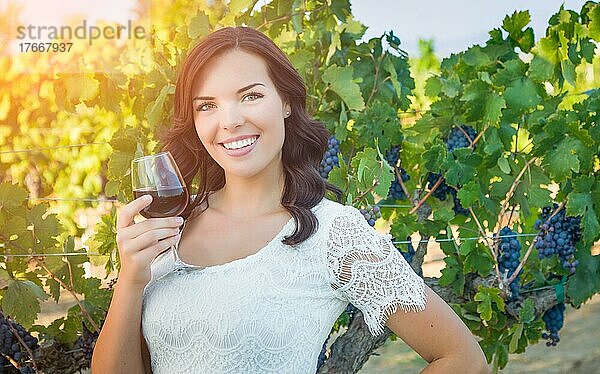 Schöne junge erwachsene Frau genießt ein Glas Weinprobe im Weinberg