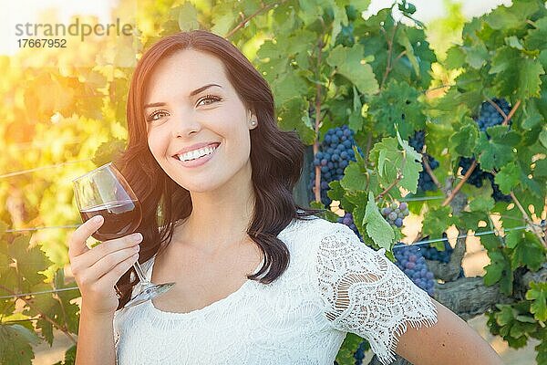 Schöne junge erwachsene Frau genießt ein Glas Weinprobe im Weinberg