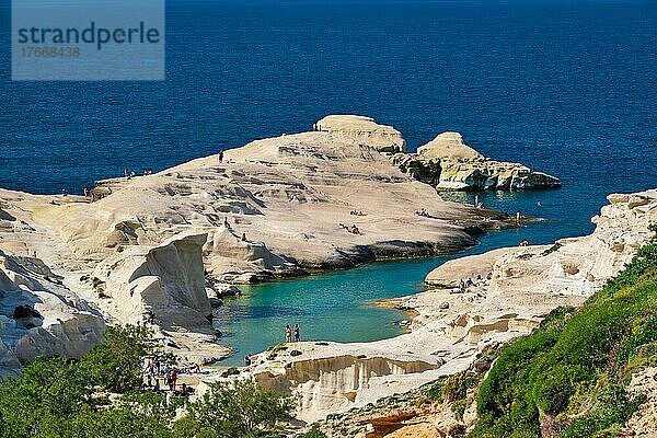 White rocks of famous tourist attraction of Milos island Sarakiniko beach with tourist relax and Aegean sea  Milos island  Greece
