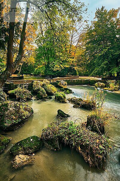 Munich English garden Englischer garten park and Eisbach river with artificial waterfall  Autumn colours on trees and leaves and flowing river  Munchen