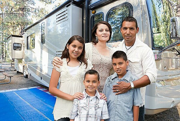 Glückliche hispanische Familie vor ihrem schönen Wohnmobil auf dem Campingplatz