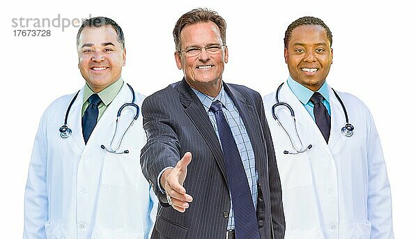 Two mixed-race doctors behind businessman reaching for a hand shake before white