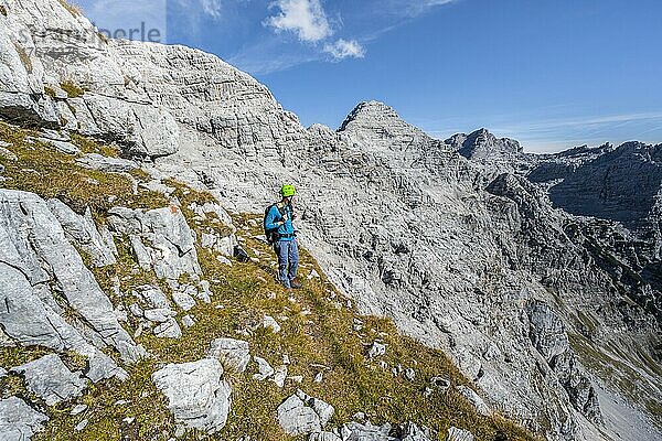 Wanderer mit Kletterhelm  auf Wanderweg  Ausblick auf Berglandschaft  hinten Gipfel des Mitterhorn  Nuaracher Höhenweg  Loferer Steinberge  Tirol  Österreich  Europa