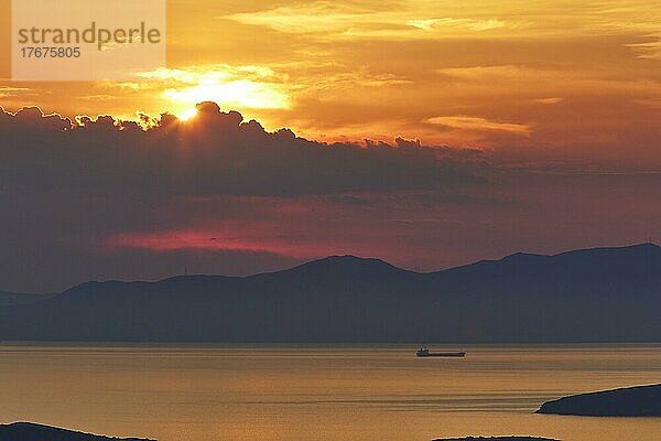 Abendhimmel orange  Sonnenuntergang  Schiff  Festland Berge im Hintergrund  Landzunge  graue Wolken  Abendhimmel rot  Westküste  Insel Andros  Kykladen  Griechenland  Europa