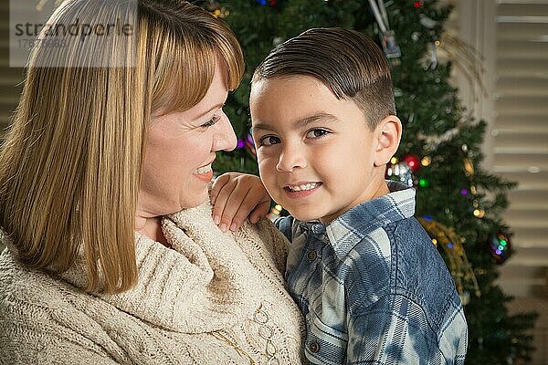 Glückliche Mutter und gemischtrassiger Sohn umarmen sich in der Nähe ihres Weihnachtsbaums