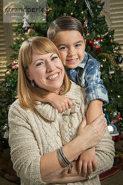 Glückliche Mutter und gemischtrassiger Sohn umarmen sich in der Nähe ihres Weihnachtsbaums