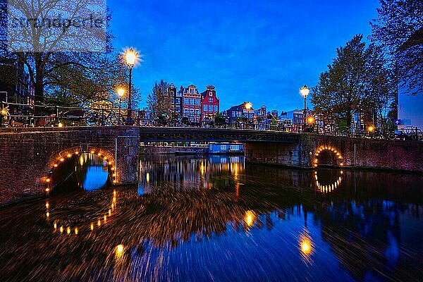 Nachtansicht der Stadt Amterdam mit Gracht  Brücke und mittelalterlichen Häusern in der Abenddämmerung beleuchtet. Amsterdam  Niederlande  Europa