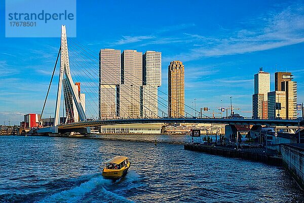 Rotterdamer Stadtbild mit Erasmus-Brücke über die Nieuwe Maas bei Sonnenuntergang mit Schnellboot unter der Brücke hindurch. Niederlande
