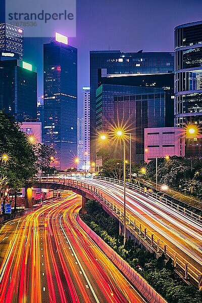 Straßenverkehr in Hongkong bei Nacht. Büro-Wolkenkratzer Gebäude und reger Verkehr auf der Autobahn Straße mit verschwommenen Autos Lichtspuren. Hongkong  China  Asien