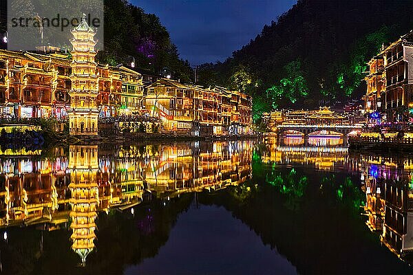 Chinesische Touristenattraktion  die alte Stadt Feng Huang (alte Stadt des Phönix) am Fluss Tuo Jiang bei Nacht beleuchtet. Provinz Hunan  China  Asien