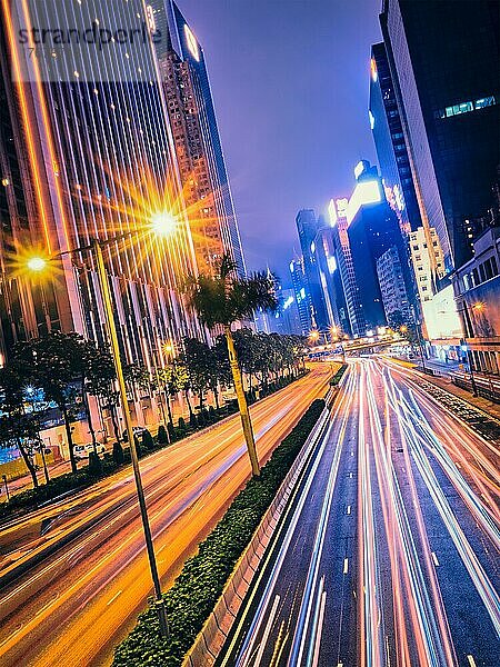 Straßenverkehr in Hongkong bei Nacht. Büro-Wolkenkratzer Gebäude und reger Verkehr auf der Autobahn Straße mit unscharfen Autos Lichtspuren. Hongkong  China  Asien