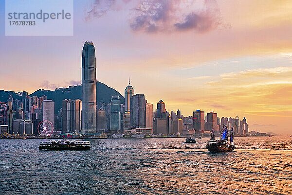 Hongkong Skyline Stadtbild Downtown Wolkenkratzer über Victoria Harbour in den Abend mit Fähre und Dschunke Boot auf Sonnenuntergang. Hongkong  China  Asien