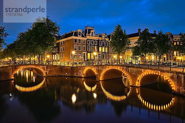 Nachtansicht der Stadt Amterdam mit Gracht  Brücke und mittelalterlichen Häusern in der Abenddämmerung beleuchtet. Amsterdam  Niederlande  Europa