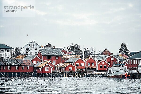 Fischerdorf Reine auf den Lofoten mit roten Rorbu-Häusern im Winter mit Schnee und Fischerbooten. Norwegen