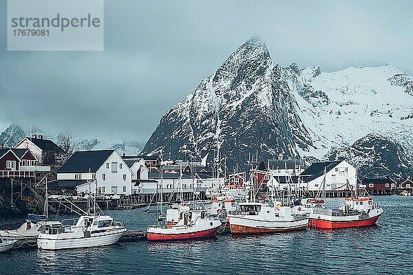 Pier mit Schiffen im Fischerdorf Hamnoy auf den Lofoten  Norwegen  mit roten Rorbu-Häusern im Winter  Europa