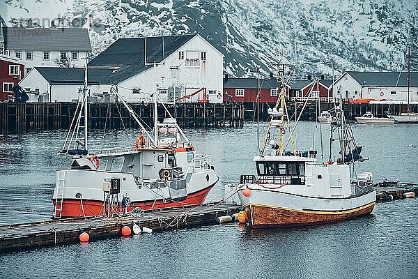 Pier mit Schiffen im Fischerdorf Hamnoy auf den Lofoten  Norwegen  mit roten Rorbu-Häusern im Winter  Europa