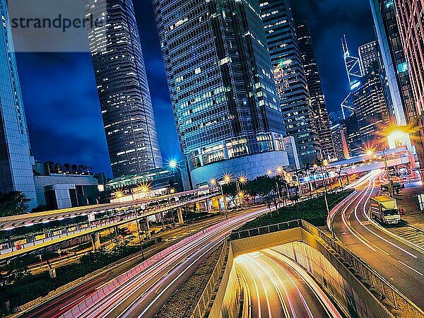 Straßenverkehr in der Nacht. Büro-Wolkenkratzer Gebäude und reger Verkehr auf der Autobahn Straße mit unscharfen Autos Lichtspuren. Hongkong  China  Asien