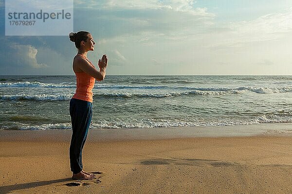 Frau macht Ashtanga Vinyasa Yoga asana Tadasana Samasthiti Yoga-Haltung am Strand