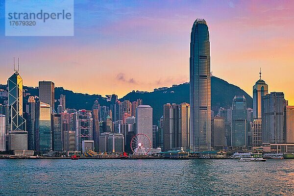 Hong Kong Skyline Stadtbild Innenstadt Wolkenkratzer über Victoria Harbour am Abend mit Dschunke Touristenfähre Boot auf Sonnenuntergang mit dramatischen Himmel. Hongkong  China  Asien
