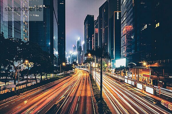 Straßenverkehr in Hongkong bei Nacht. Büro-Wolkenkratzer Gebäude und reger Verkehr auf der Autobahn Straße mit unscharfen Autos Lichtspuren. Hongkong  China  Asien