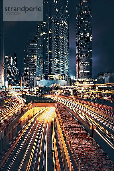 Straßenverkehr in Hongkong bei Nacht. Büro-Wolkenkratzer Gebäude und reger Verkehr auf der Autobahn Straße mit verschwommenen Autos Lichtspuren. Hongkong  China  Asien
