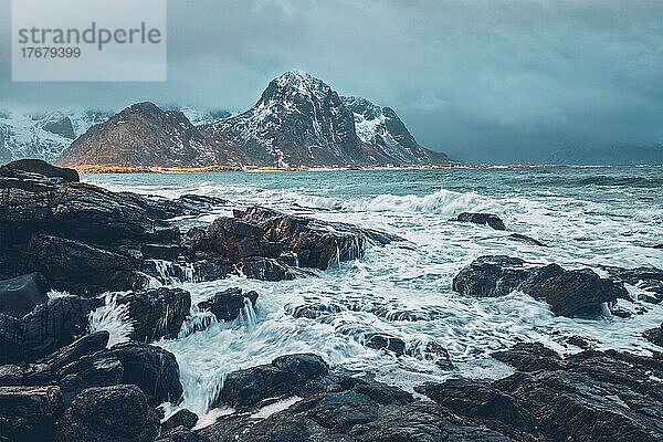 Wellen  die an Felsen an der felsigen Küste eines Fjords im norwegischen Meer im Winter zerschellen. Lofoten Inseln  Norwegen  Europa
