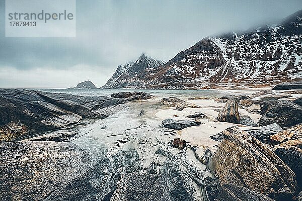 Felsküste des Fjords der norwegischen See im Winter mit Schnee. Haukland Strand  Lofoten Inseln  Norwegen  Europa