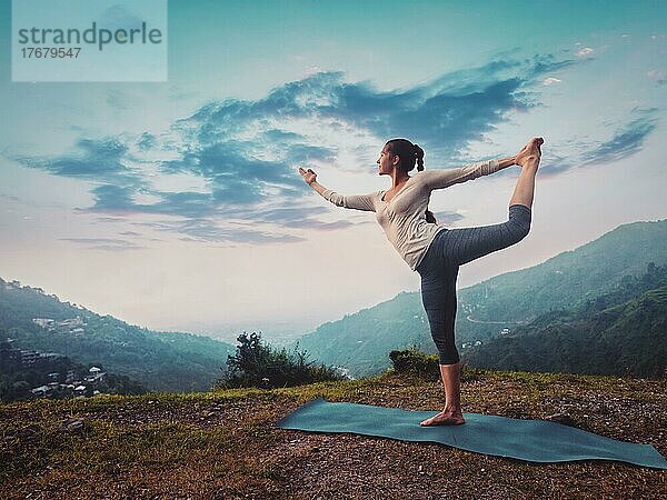 Frau macht Yoga-Asana Natarajasana  Lord of the Dance Pose im Freien bei Sonnenuntergang im Himalaya. Vintage Retro-Effekt gefiltert Hipster-Stil Bild