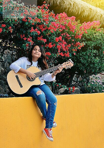 Ein Mädchen sitzt und spielt Gitarre im Freien  Porträt eines lächelnden Mädchens beim Gitarrenspiel  Lebensstil eines Mädchens beim Gitarrenspiel im Freien
