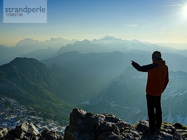 Bergsteiger am Gipfel des Krn 2. 244m zeigt auf sein nächstes Ziel  Triglav-Nationalpark  Julische Alpen  Slowenien  Europa