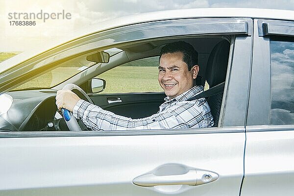 Mann lächelt in seinem Auto in die Kamera  Mann lächelt glücklich in seinem Auto  Bild einer lächelnden und glücklichen Person  die ein Auto fährt und in die Kamera schaut