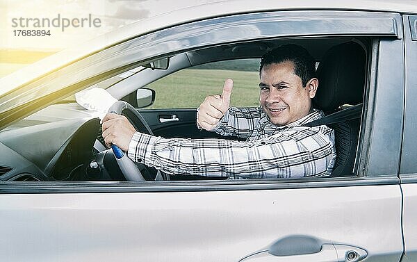 Porträt eines Mannes  der beim Fahren die Daumen nach oben zeigt  Mann im Auto  der die Daumen nach oben zeigt  glücklicher Mann im Auto