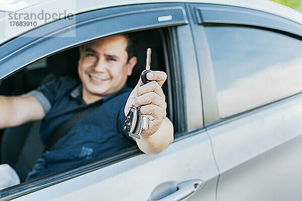 Ein Mann in seinem Fahrzeug zeigt seine neuen Autoschlüssel  ein glücklicher Mann zeigt die Schlüssel seines neuen Autos  Person in seinem Fahrzeug zeigt seine Autoschlüssel  Fahrzeugvermietung Konzept