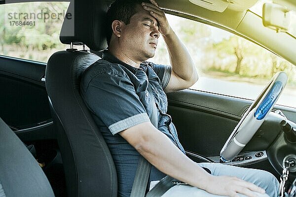 Eine Person im Auto mit Kopfschmerzen  Konzept eines Mannes in seinem Auto mit Kopfschmerzen  Ein Autofahrer mit Kopfschmerzen  Ein Fahrer mit Stress und Migräne