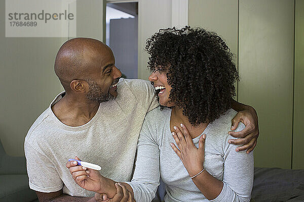 Lächelndes Paar hält Schwangerschaftstest-Kit in der Hand
