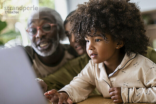 Lächelnde Großeltern mit Enkelin  die Laptop benutzen