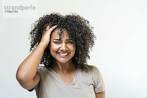Smiling woman standing against white wall