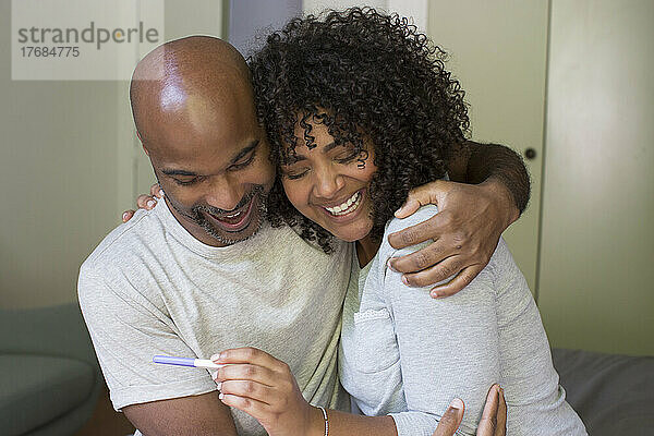 Glückliches Paar hält Schwangerschaftstest-Kit in der Hand