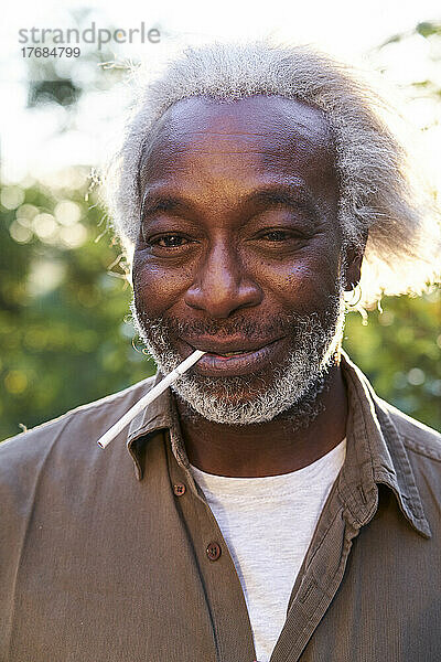 Close-up of a senior man holding cigarette in his mouth