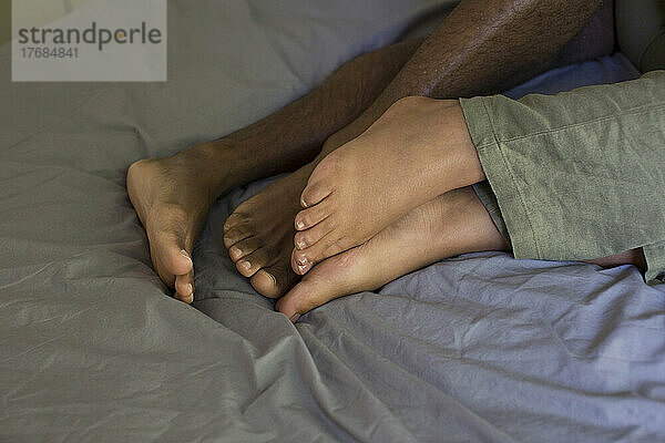 Feet of young couple lying on bed